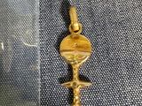 une photo d'un pendentif en forme de clé plaqué or posé sur un tissu bleu