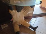 une statue représentant un homme assis par terre, avec une table en verre posée sur la tête