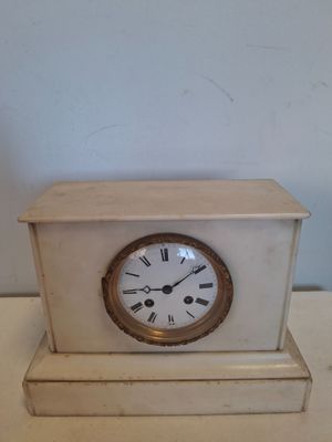 une petite horloge blanche posée sur une table