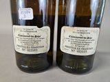 two bottles of wine with labels on them sitting on a table