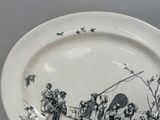 a black and white plate with a drawing of people on it