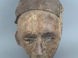 un vieux masque en bois au visage brun et coiffé d'un chapeau brun