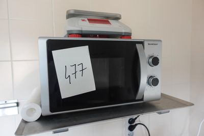 un micro-ondes posé sur une étagère, avec un bout de papier dessus