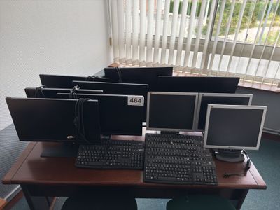 a lot of computer monitors and keyboards on the desk