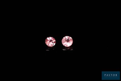a pair of pink diamond earrings on a black background