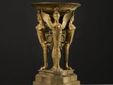 un vase antique en bronze orné d'une femme et de deux hommes
