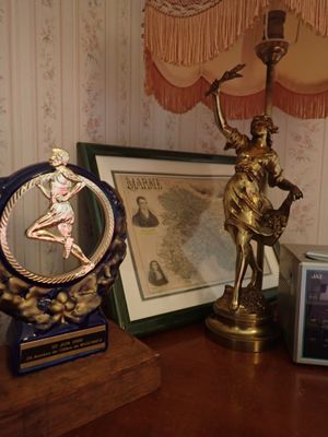 une table sur laquelle se trouvent une lampe, un cadre photo et une statue