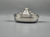 a silver plate with a lid on a gray surface