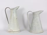 two metal pitchers sitting next to each other on a table