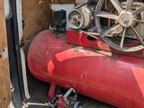 a red air compressor sitting in the back of a van