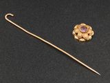 un gros plan d'une broche en or ornée d'une pierre violette