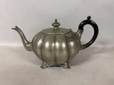 une théière ancienne en argent avec une poignée noire sur une surface blanche