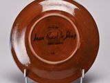 an orange plate with a black writing on it sitting on a metal stand