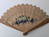 a wooden fan with flowers on it hanging on a wall