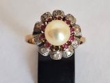 un gros plan d'une bague en perle et diamant posée sur un socle noir