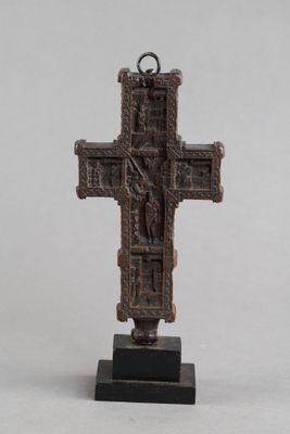 une vieille croix en bronze posée sur un socle noir, sur fond blanc