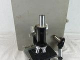 an old microscope with a metal case on a white surface