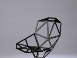 La chaise est en béton et présente un design géométrique.