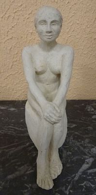 a white statue of a woman sitting on a black table