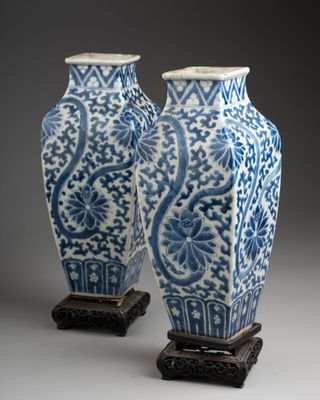pair of chinese blue and white vases on stands on a gray background