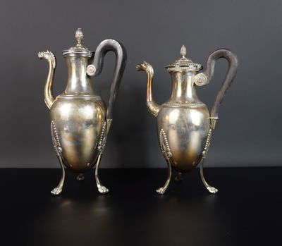 une paire de théières anciennes en métal argenté posées sur une table noire