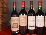 six bottles of red wine are lined up on a table