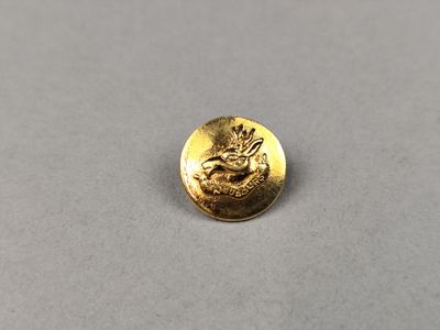 un gros plan d'un bouton doré sur une surface grise