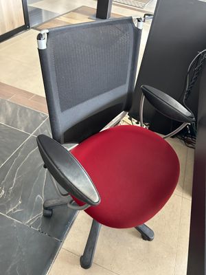 a red office chair sitting in front of a black desk