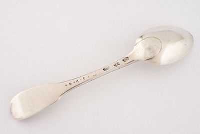 une cuillère en argent posée sur une surface blanche, avec une petite cuillère au milieu