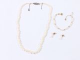 a necklace, bracelet, and earring set on a white surface