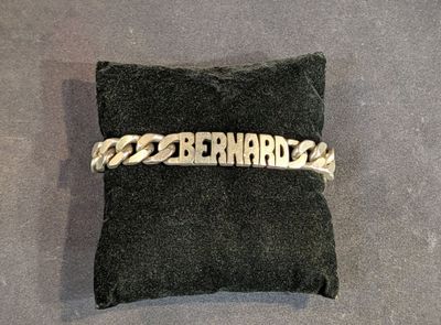 un bracelet à chaîne en argent avec un prénom gravé, posé sur un coussin noir