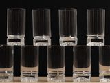 several shot glasses are lined up on a table with a black background