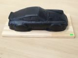 un gâteau noir orné d'une voiture, posé sur une planche en bois