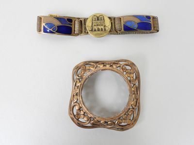 two pieces of gold and blue jewelry on a white surface