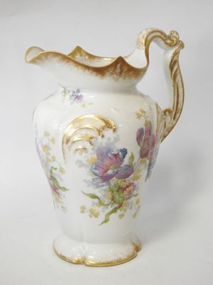 a white vase with flowers on it on a white surface