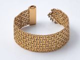 gros plan d'un bracelet en or sur une surface blanche