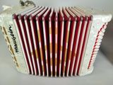 an old red and white accordion sitting on top of a white table