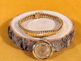 bracelet with a coin on a wooden stand on a yellow background