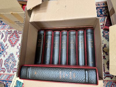 six books in a cardboard box on a carpet
