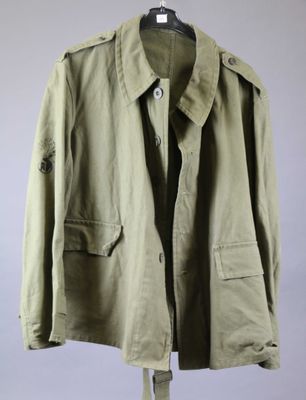 a green jacket hanging on a hanger on a gray wall