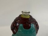 a green and brown vase with a brown top