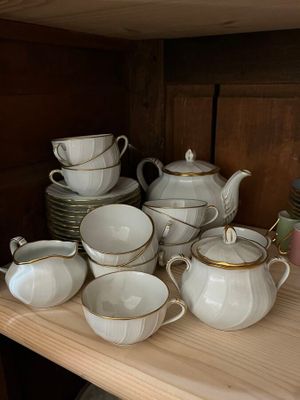 many cups and saucers on a shelf in the kitchen