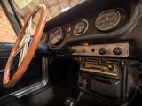 steering wheel and dashboard of a classic car with a brick wall in the background