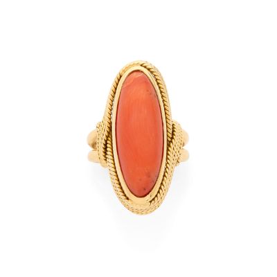 une bague en or ornée d'une pierre de corail ovale au centre