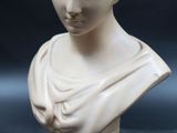 marble bust of a woman on a wooden base on a black background