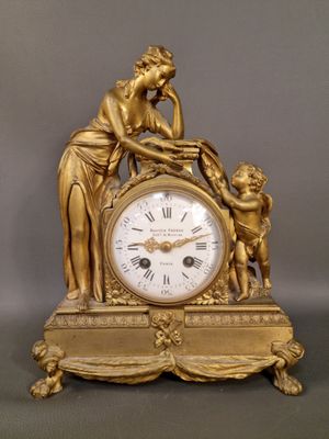 une horloge en or sur laquelle sont représentés une femme et un enfant
