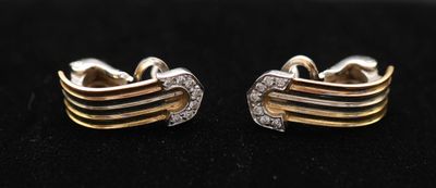 une paire de boucles d'oreilles en or et diamants sur une surface noire