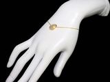 gold plated bracelet with a heart charm on a mannequin ' s hand
