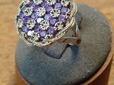 bague en argent sertie d'améthoralite et de diamants, présentée sur un socle en bois