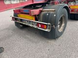 un poids lourd rouge avec une remorque à plateau garé sur un parking